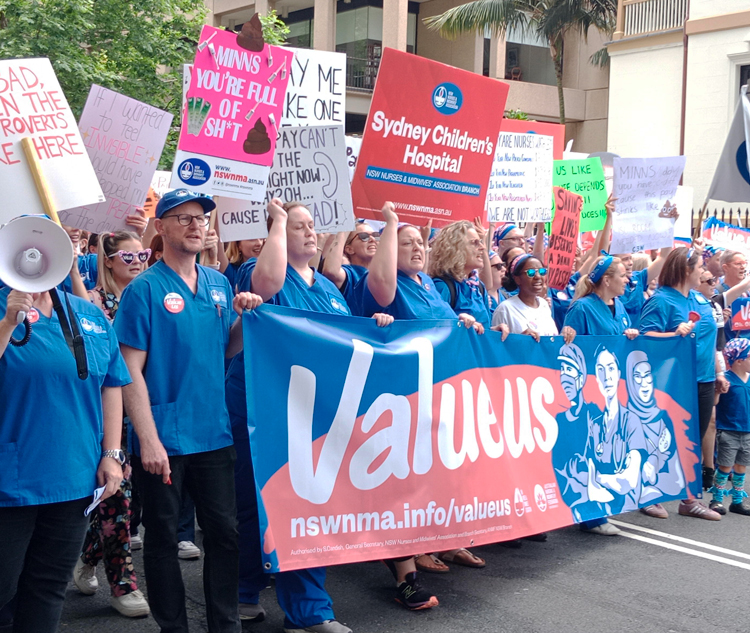 Thousands of nurses and midwives march in Sydney and rally at the New South Wales state Parliament there as part of a 24-hour strike demanding an immediate 15% pay raise.