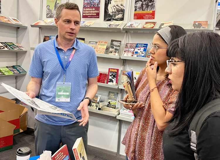 Jacob Perasso, SWP member and volunteer at Pathfinder booth, discusses Pathfinder books with two call center workers at Guadalajara International Book Fair in Mexico Dec. 4.