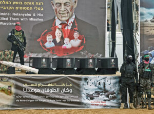 Hamas parades coffins of dead Israeli hostages Oded Lifshitz, Shiri Bibas and her two children, Kfir and Ariel, Feb. 20 in Khan Younis, Gaza, before returning bodies to Israel. Caskets say “Date of arrest” Oct. 7. Banner on stage threatens “Al-Aqsa flood was our promise” to launch more pogroms killing Jews.