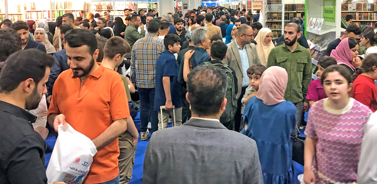Arriba, Feria Internacional del Libro de Erbil, 11 de abril. En el stand de Pathfinder, el voluntario Steve Penner conversa con visitantes sobre libros de dirigentes del Partido Socialista de los Trabajadores y otros revolucionarios. Penner es un dirigente de la Liga Comunista en Canadá.