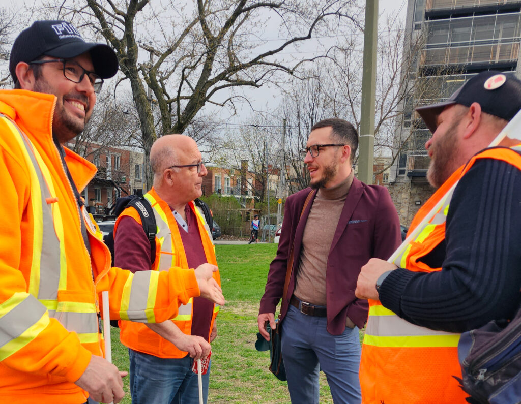 Le 1er mai à Montréal, Philippe Tessier, deuxième à droite, cheminot et candidat de la Ligue communiste, parle avec des travailleurs de cimenterie en lock-out. « Nous devons défendre nos intérêts de classe » a-t-il dit.