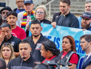 Kilmar Abrego García speaks at Baltimore rally before reporting to ICE officials Aug. 25. At left is his wife, Jennifer Vásquez Sura; his brother, César, stands behind him. At right is his lawyer.