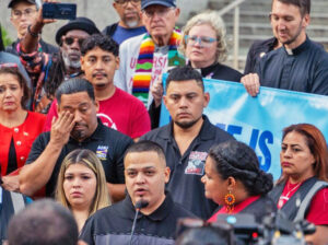 Kilmar Abrego García speaking at Baltimore rally before reporting to ICE officials Aug. 25. His wife, Jennifer Vásquez Sura, stands to his right; his brother, César, stands behind him.
