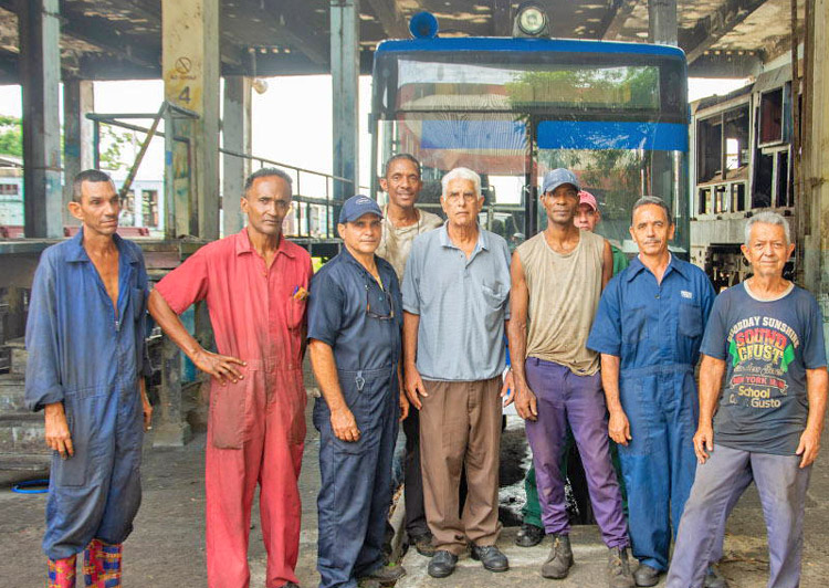 Cuban rail workers pose with “El Mayor,” big bus they adapted to run on tracks from old sugar plantations to the cities, using creativity and determination, opening travel from rural areas.