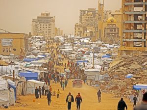 Palestinians walk through Gaza City during sandstorm Feb. 13. Millions of Gazans were displaced as a result of Hamas’ practice of placing command posts, weapons, inside hospitals and in tunnels underneath people’s homes. Now Hamas thugs are preventing workers in Gaza from building apartments for tens of thousands of Palestinians in Israeli-occupied Rafah.