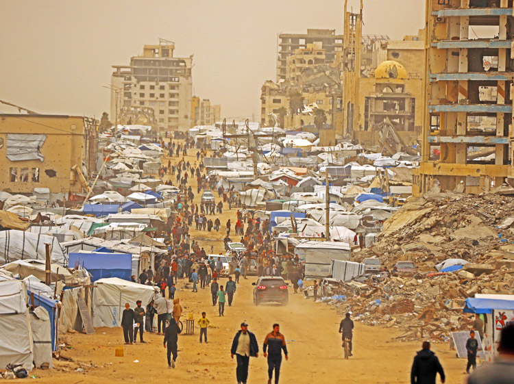 Palestinians walk through Gaza City during sandstorm Feb. 13. Millions of Gazans were displaced as a result of Hamas’ practice of placing command posts, weapons, inside hospitals and in tunnels underneath people’s homes. Now Hamas thugs are preventing workers in Gaza from building apartments for tens of thousands of Palestinians in Israeli-occupied Rafah.