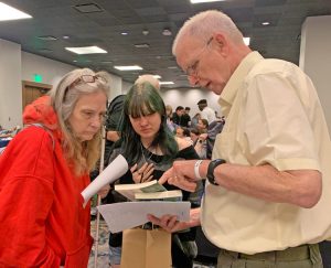 Janice Grisham, president of Springfield, Missouri, chapter of National Federation of the Blind, with granddaughter Morgan Long, who buys three Pathfinder titles from exhibitor Bob Roberts at NFB’s convention in Austin, Texas, in July. Some 2,700 people took part in the proceedings.