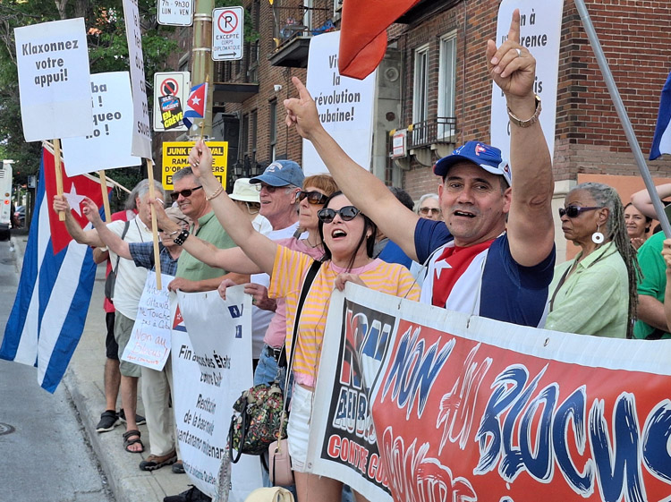 Protest in defense of Cuba outside Cuban Consulate in Montreal, one of several across world July 26, demands end of U.S. economic blockade. Sign top left says, “Honk to show support.”